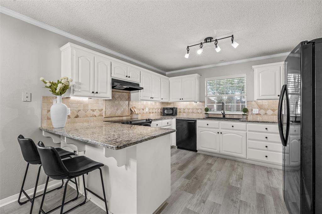 112 Briar Ridge Drive Hewitt, TX 76643 - Photo 6 of 15 Kitchen featuring white cabinetry, granite countertops, an undermount sink, a tiled backsplash, and wood-finish flooring