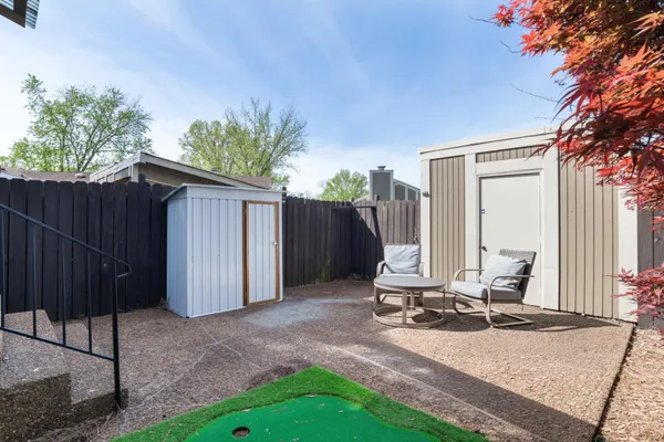 a view of a backyard with a chair and potted plants