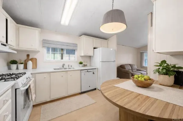 a kitchen with stainless steel appliances a sink a table chairs and white cabinets