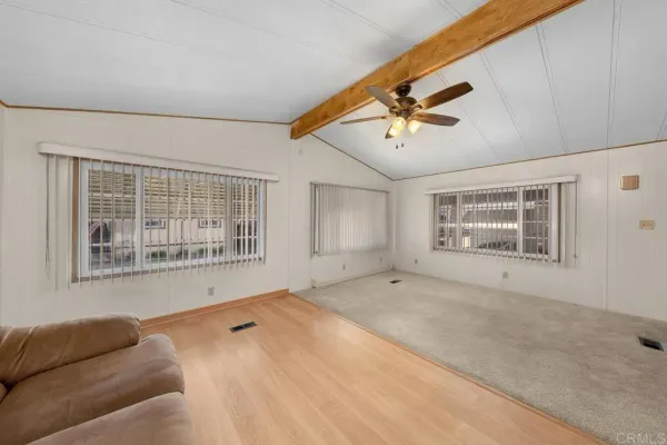 a view of an empty room with a window and a kitchen