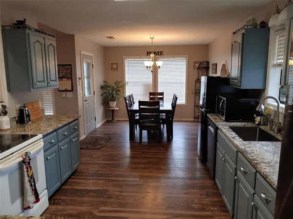 a kitchen with stainless steel appliances granite countertop wooden floors stove top oven with a dining table and chairs