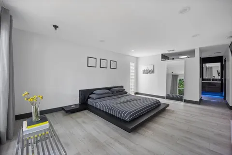 a spacious bedroom with a bed and wooden floor
