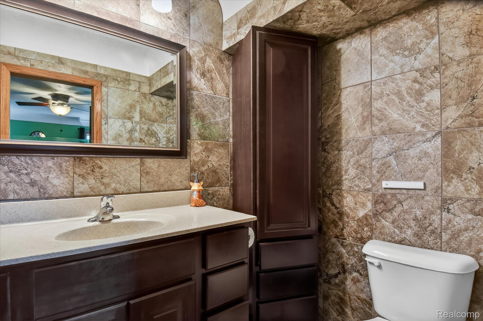 3949 West Burns Line Road Brown City, MI 48416 - Photo 30 of 70 Bathroom featuring large format stone-look wall tiles, a dark wood-finish vanity with an integrated sink, and a framed wall mirror