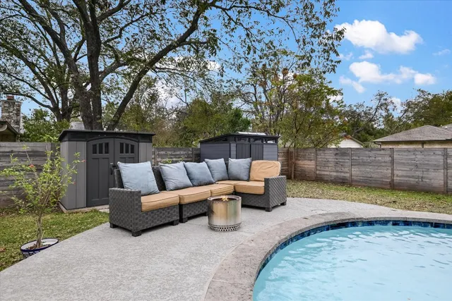 a view of a patio with couches table and chairs and wooden fence