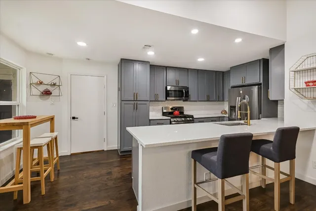 a kitchen with refrigerator a chair and wooden cabinets