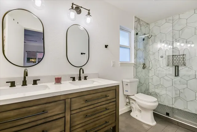 a bathroom with a double vanity sink toilet mirror and shower