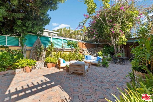 a view of a patio with table and chairs potted plants and large tree
