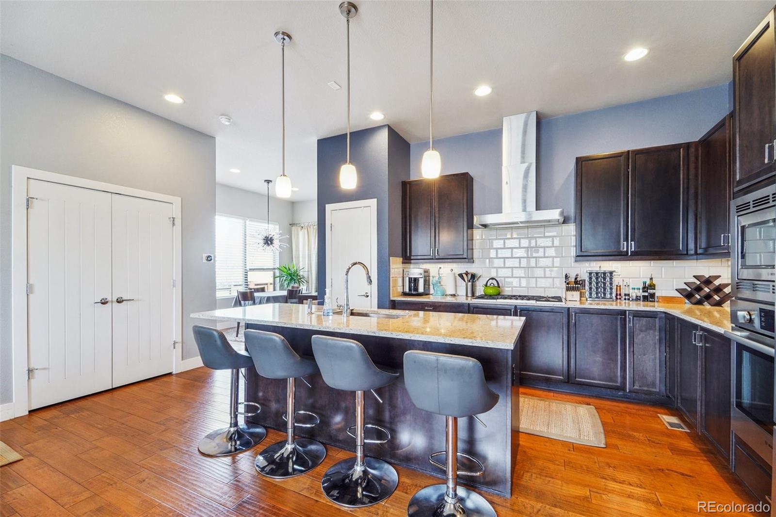 a kitchen with stainless steel appliances granite countertop a sink a stove a dining table and chairs