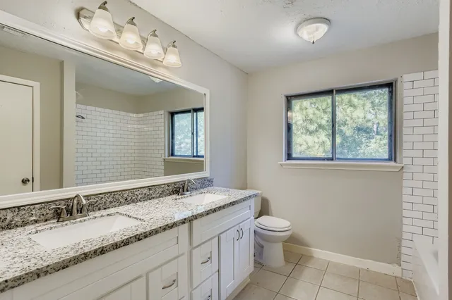 a bathroom with a granite countertop sink a toilet and a mirror