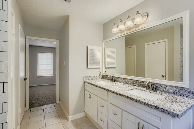 a bathroom with a granite countertop sink and a mirror
