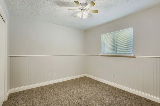 an empty room with a window and a ceiling fan