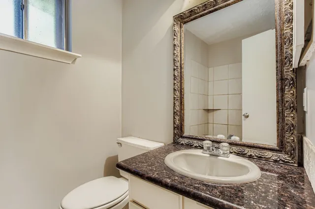 a bathroom with a granite countertop sink toilet and mirror