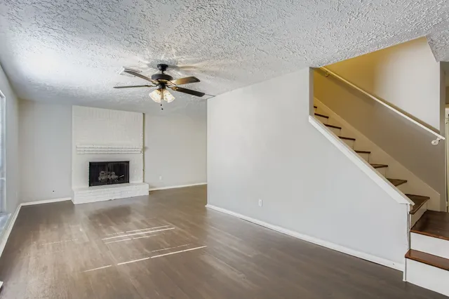 a view of an empty room with a fireplace and a ceiling fan