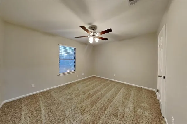 an empty room with a window and a ceiling fan