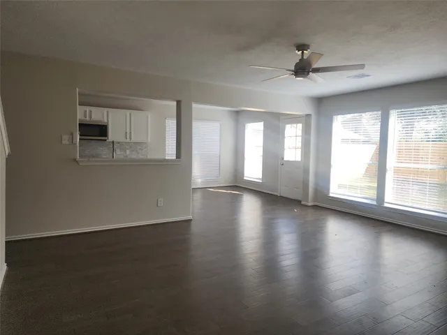 a view of an empty room with a window and wooden floor