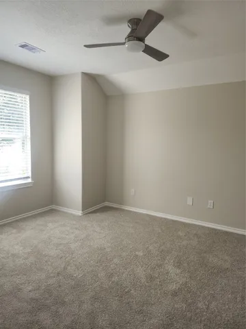 an empty room with a ceiling fan and windows