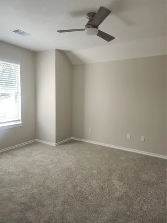 an empty room with a ceiling fan and windows