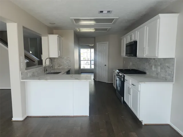 a kitchen with granite countertop a sink and a stove top oven