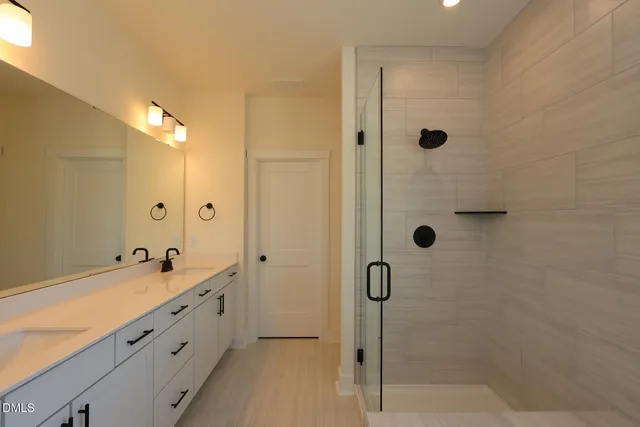 a bathroom with a double sink shower and mirror