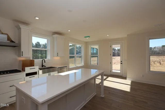 a living room with stainless steel appliances granite countertop a sink and a large window
