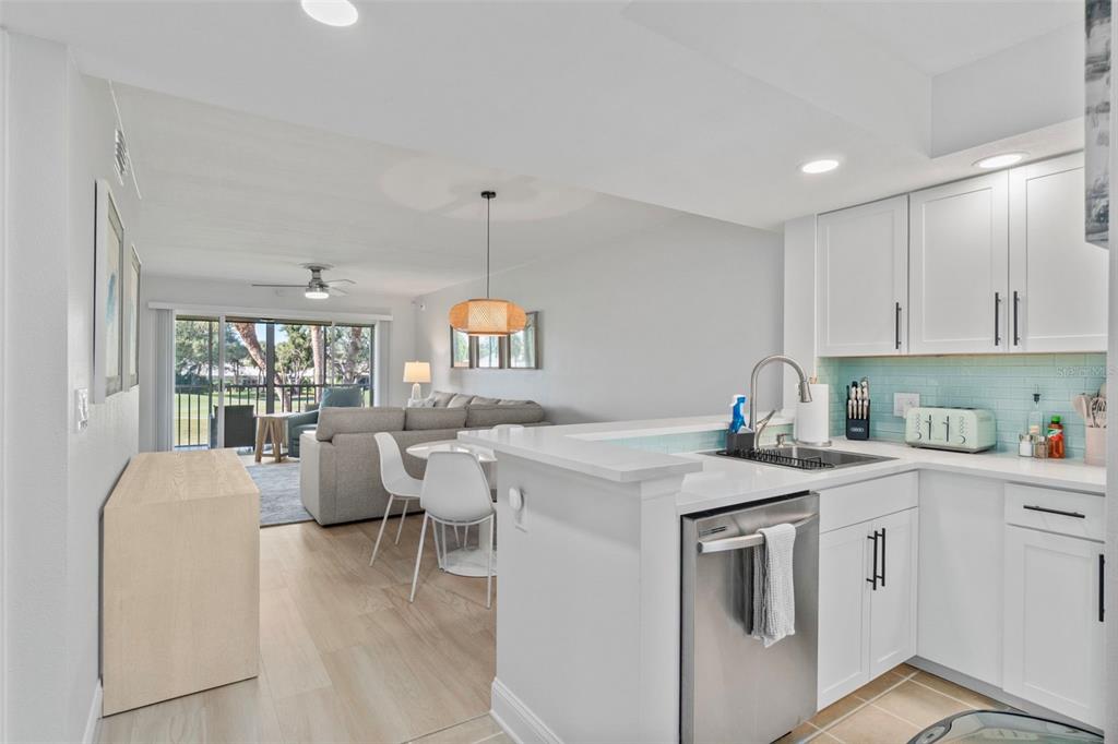 433 Cerromar Lane, Unit 441 Venice, FL 34293 - Photo 4 of 65 a open kitchen with stainless steel appliances granite countertop a stove top oven a sink a dining table and chairs with white cabinets