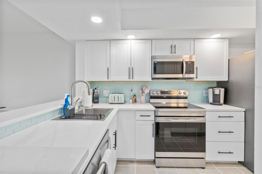 433 Cerromar Lane, Unit 441 Venice, FL 34293 - Photo 5 of 65 a kitchen with a microwave and white cabinets