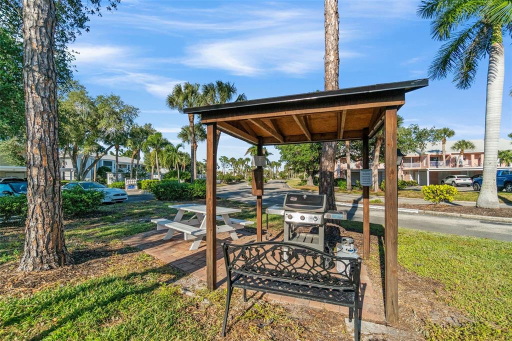 433 Cerromar Lane, Unit 441 Venice, FL 34293 - Photo 57 of 65 a view of a patio with table and chairs under an umbrella with a small yard