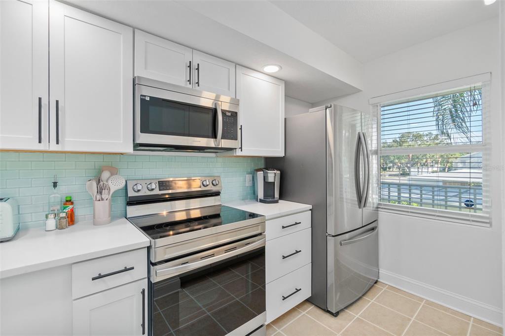 433 Cerromar Lane, Unit 441 Venice, FL 34293 - Photo 6 of 65 a kitchen with stainless steel appliances a refrigerator stove and microwave