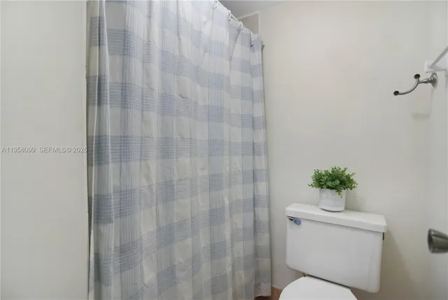 a white toilet sitting next to a shower curtain