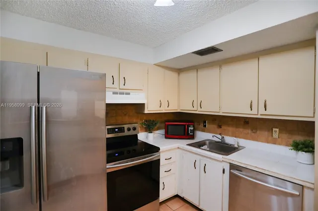 a kitchen with a refrigerator sink and cabinets
