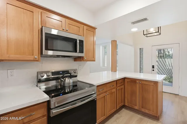a view of an empty room with wooden floor and a ceiling fan