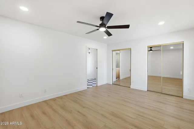 an empty room with wooden floor fan and windows