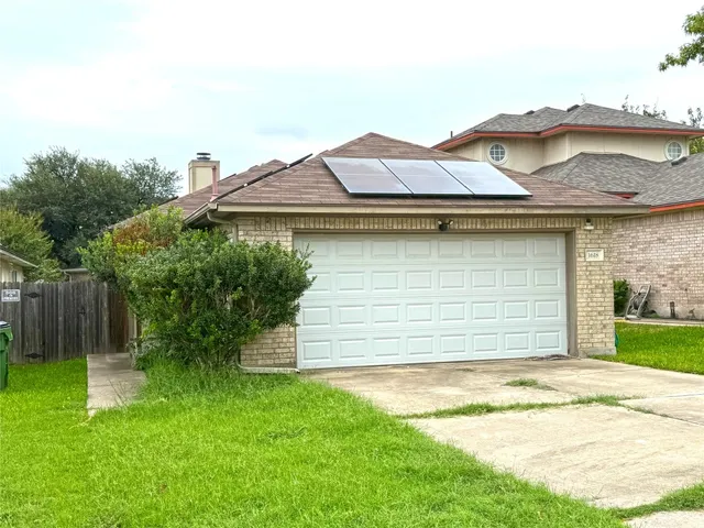 a view of a house with a yard plants and large tree