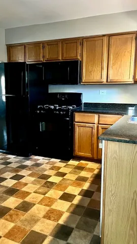 a kitchen with granite countertop a refrigerator and a stove top oven