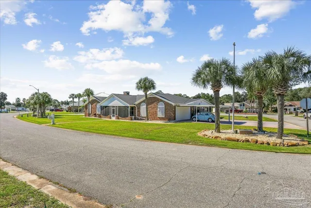 a view of a house with a big yard and palm trees