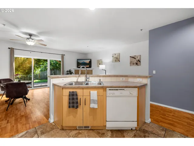 a kitchen with stainless steel appliances granite countertop a stove a sink dishwasher and a dining table with garden view