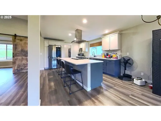 a kitchen with kitchen island granite countertop a sink cabinets and wooden floor