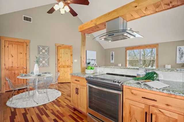 a kitchen with stainless steel appliances granite countertop a stove a sink dishwasher and cabinets with wooden floor