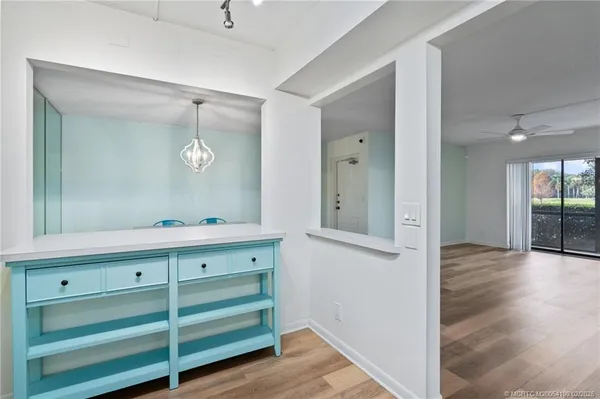 a view of an empty room with wooden floor and a mirror
