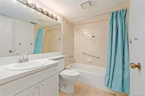 a bathroom with a toilet a sink a mirror a bathtub and shower
