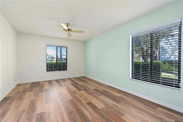 a view of an empty room with a window and wooden floor