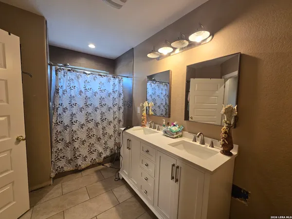 a spacious bathroom with a double vanity sink mirror and shower