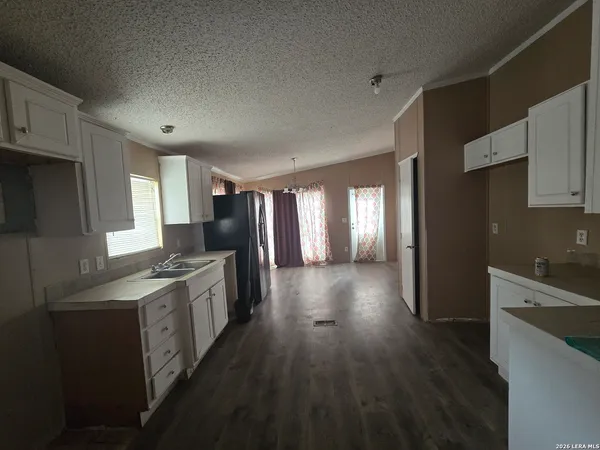 a kitchen with stainless steel appliances granite countertop a refrigerator a sink dishwasher a stove and white countertops with wooden floor