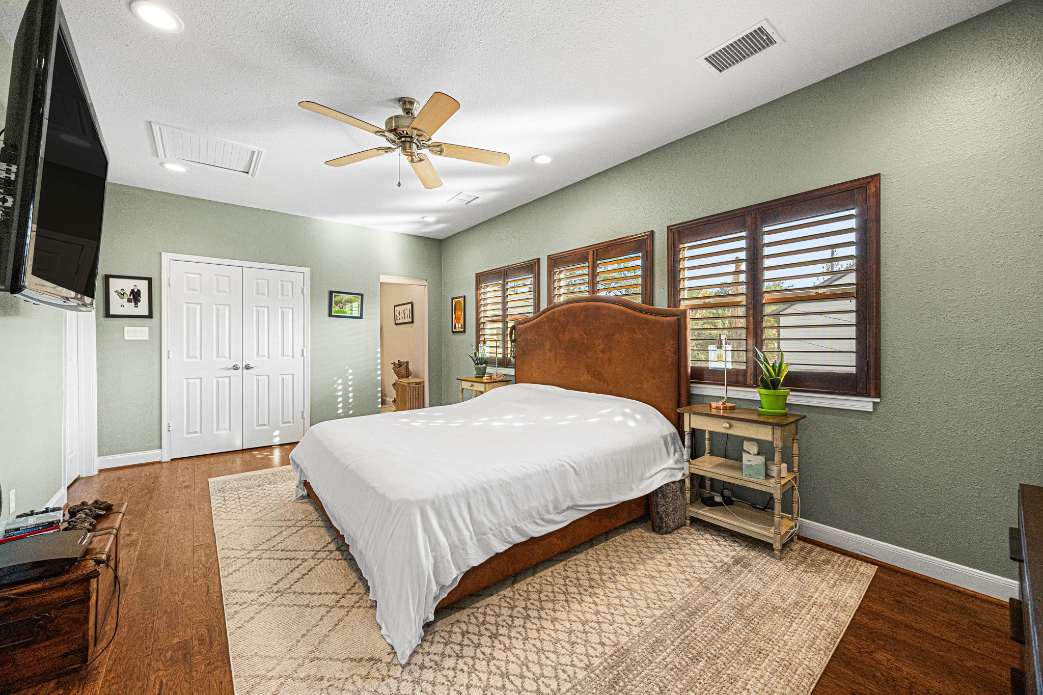 202 East 7th Street Houston, TX 77007 - Photo 16 of 27 Primary suite showcasing wood floors, large windows with shutters, and a calm, inviting layout.