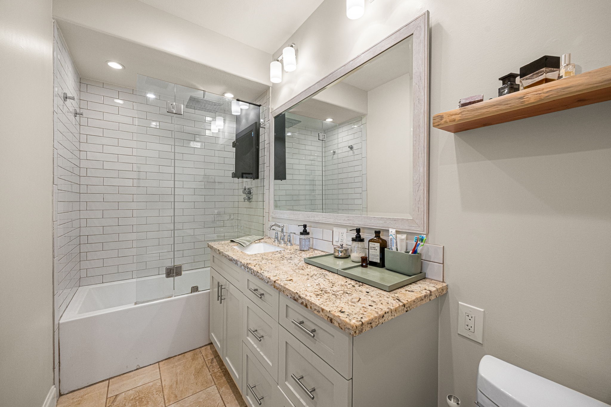202 East 7th Street Houston, TX 77007 - Photo 18 of 27 Bright and modern bath with granite vanity, subway tile surround, oversized mirror, and contemporary lighting.