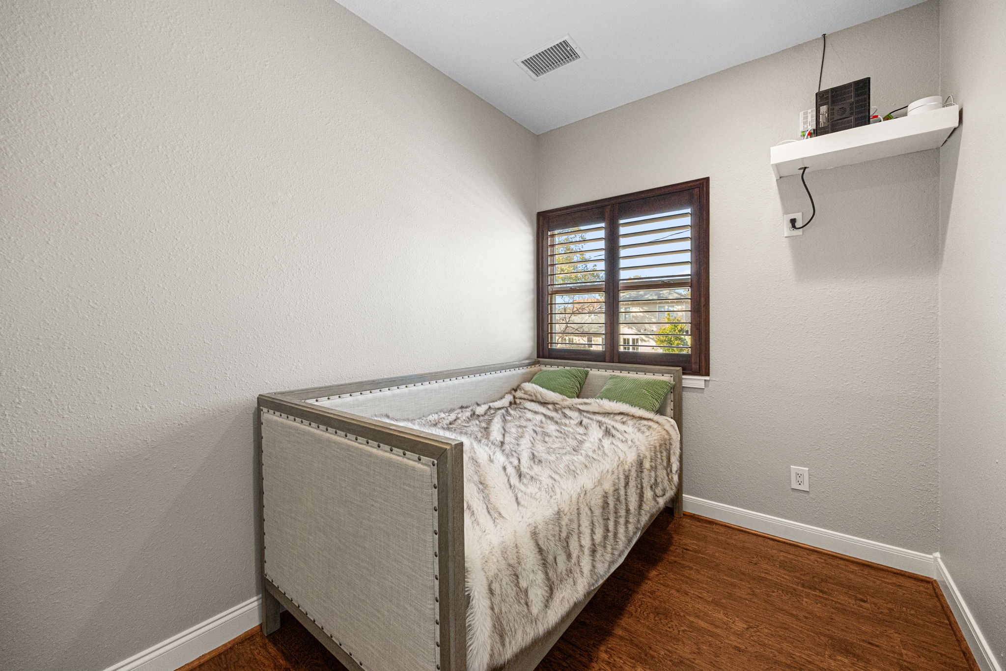 202 East 7th Street Houston, TX 77007 - Photo 20 of 27 Cozy secondary bedroom with warm wood flooring, neutral walls, and plantation shutters allowing for natural light and privacy.