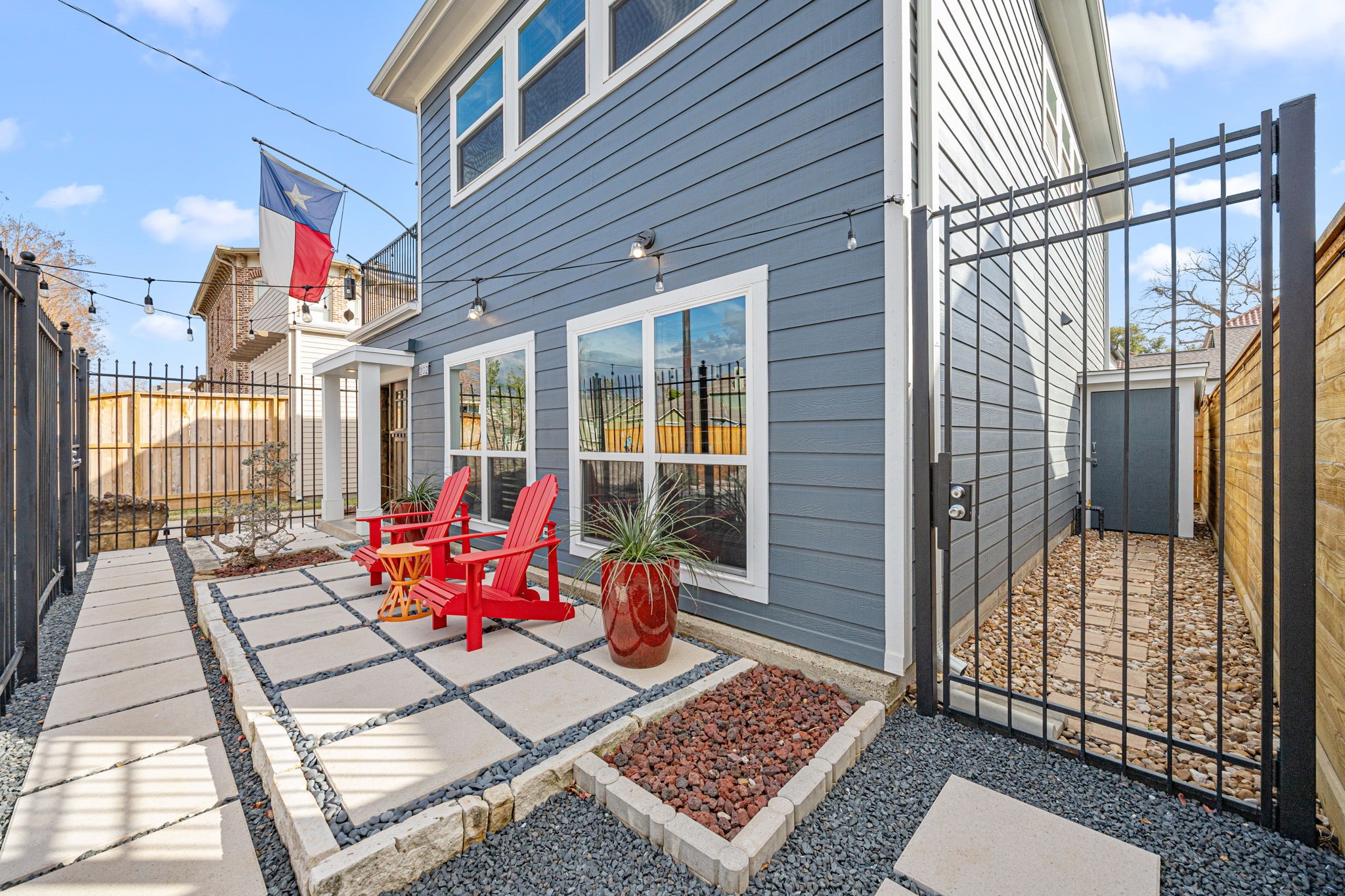 202 East 7th Street Houston, TX 77007 - Photo 25 of 27 Stylish front patio featuring stone pavers, café lighting, and seating area—perfect for outdoor relaxation or entertaining. Additional outdoor storage is shown here.