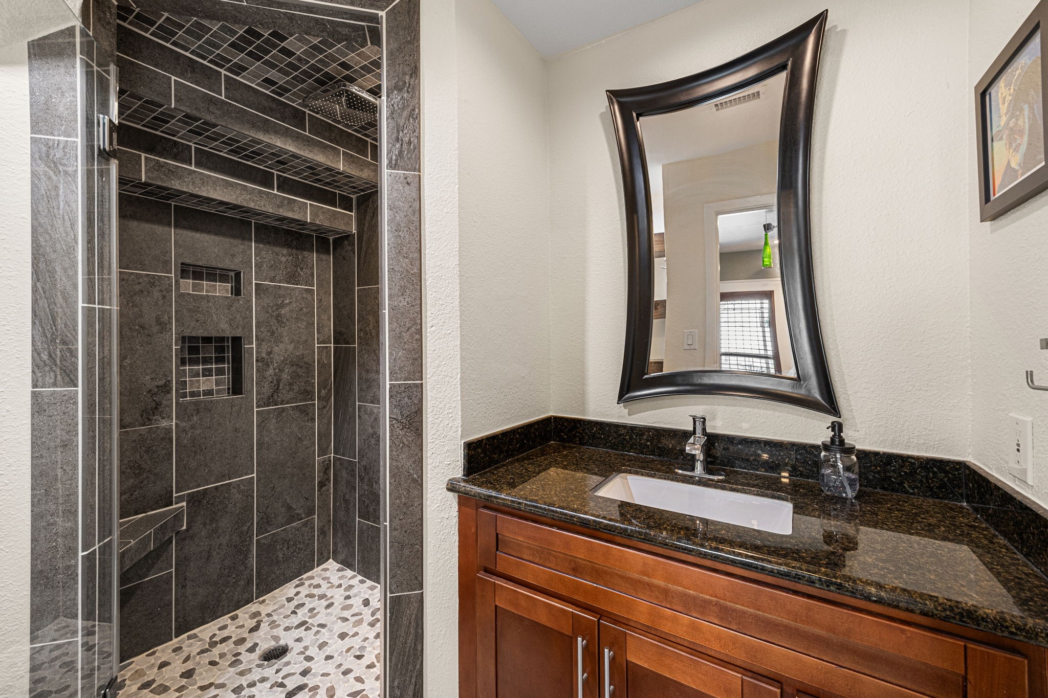 202 East 7th Street Houston, TX 77007 - Photo 10 of 27 Spa-inspired bathroom featuring a custom tiled walk-in shower with built-in bench, designer niche, and pebble stone flooring for a luxury feel. Located on the 1st floor for guests and downstairs bedroom.