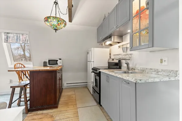 a kitchen with stainless steel appliances granite countertop a refrigerator a sink dishwasher a stove a dining table and chairs with wooden floor