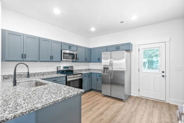 a large kitchen with stainless steel appliances granite countertop a stove and a sink